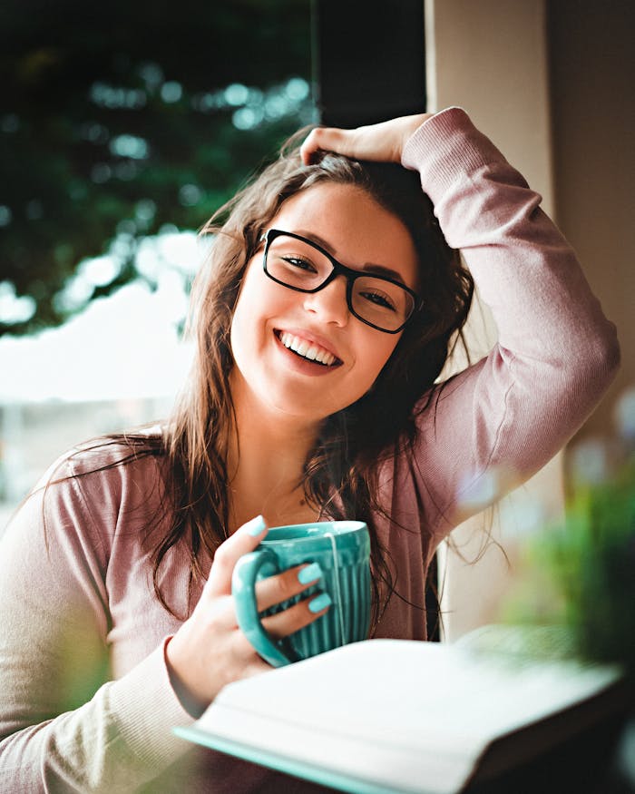 Young woman enjoying a relaxing moment with a tea cup and book outdoors.